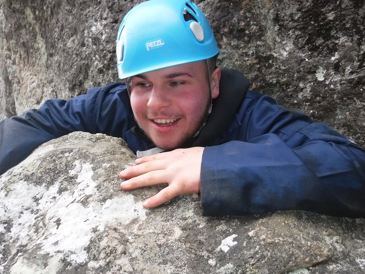 Young boy climbing through a narrow gap weasling